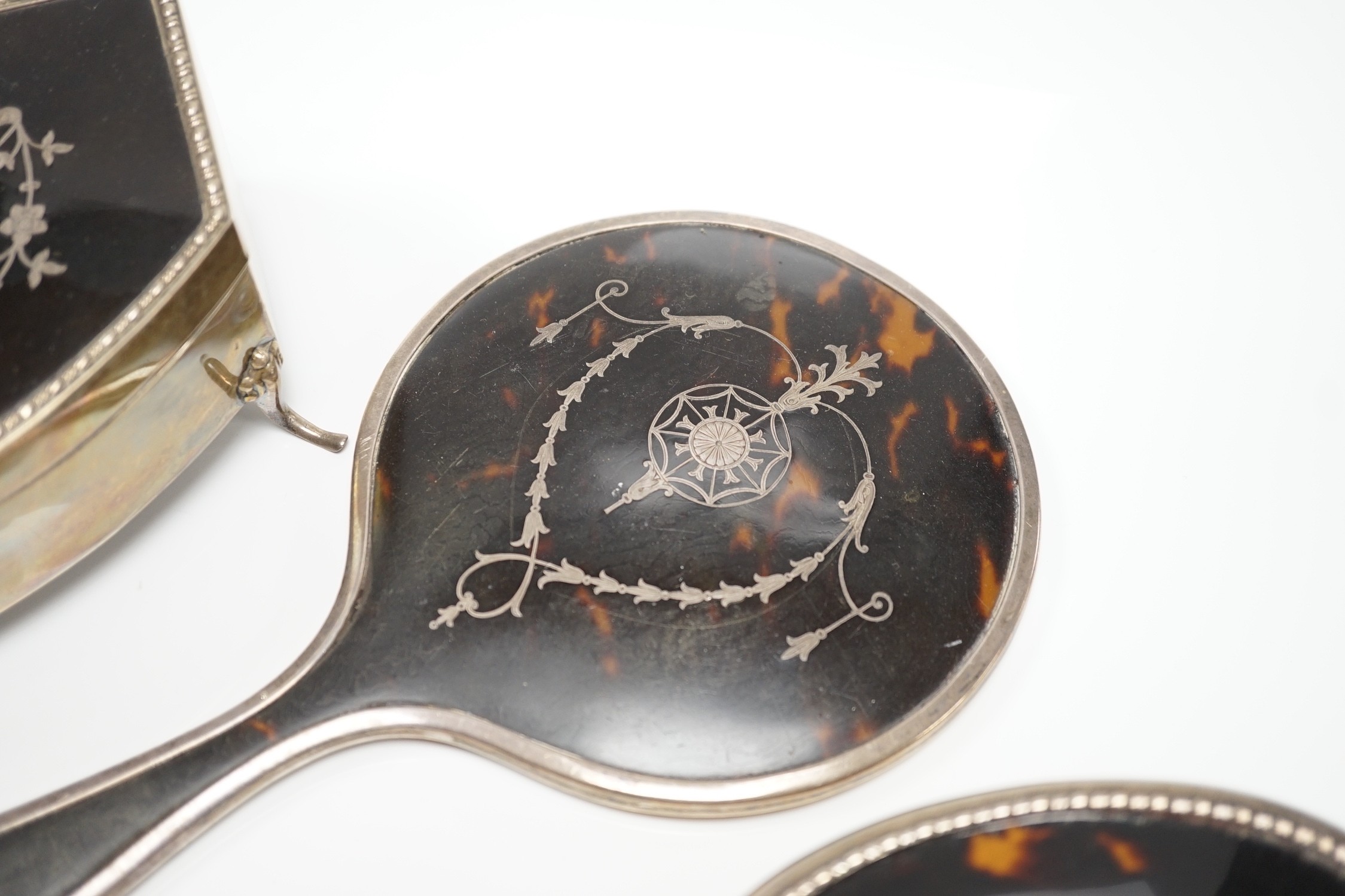 A George V silver and tortoiseshell piqué mounted trinket box, Levi & Salaman, Birmingham, 1918, 19cm and a matched three piece silver and tortoiseshell mounted mirror and brush set.